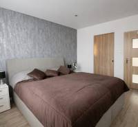 NOVINKA - Priestranných 74 m² v štýlovo zariadenom byte - Spálňa v 3-izbovom byte s posteľou a stenou s textúrovaným dekorom, podlaha s dreveným dekorom.