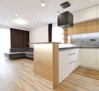 Na PRENÁJOM_v NOVOSTAVBE krásny 3-izbový byt s parkovacím státím - Interiér 3-izbového bytu s kuchyňou, sedačkou a podlahou s dreveným dekorom.