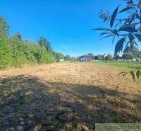 Stavebný pozemok pri Nitre so stavebným povolením v tichej lokalite - Pozemok na bývanie obklopený zeleňou v Hosťovej za slnečného počasia.