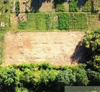 Stavebný pozemok pri Nitre so stavebným povolením v tichej lokalite - Pozemky - bývanie v Hosťovej, lúka s okolitými zelenými parcelami viditeľnými z výšky.