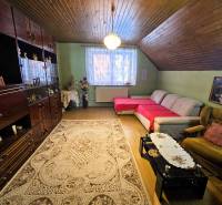Predaj 5-izbový dom v Kameňanoch, okres Revúca - Obývačka s kobercom, pohovkou a podlahou s dreveným dekorom v rodinnom dome.