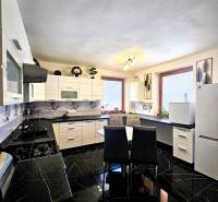 Predaj 5-izbový dom v Kameňanoch, okres Revúca - Kuchyňa v rodinnom dome s čiernym lesklým obkladom a bielym nábytkom.