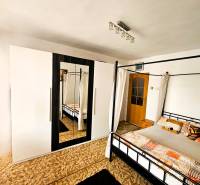 Predaj 5-izbový dom v Kameňanoch, okres Revúca - Spálňa v rodinnom dome s posteľou, kobercom a skriňou so zrkadlom.