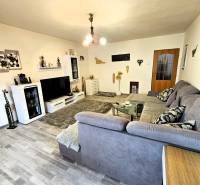 Predaj 5-izbový dom v Kameňanoch, okres Revúca - Obývačka v rodinnom dome s podlahou s dreveným dekorom, šedou sedačkou a moderným osvetlením.