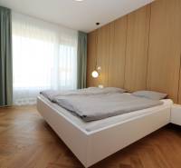 NUERA︱Penthouse s terasou s krásnymi výhľadmi v Dúbravke - Spálňa v 4-izbovom byte s podlahou s dreveným dekorom, bielym nábytkom a veľkým oknom.