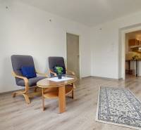 Na PRENÁJOM, VEĽKÝ 2 izb. TEHLOVÝ BYT, SÍDLISKO II., PREŠOV  - Obývacia izba v 2-izbovom byte s podlahou s dreveným dekorom a pohodlnými kreslami.