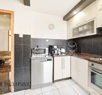 Na predaj 4-izb. byt s loggiou , Dunajská Streda - Kuchyňa v 4-izbovom byte s čiernymi obkladmi a spotrebičmi, podlaha s dreveným dekorom.