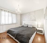 Na predaj 4-izb. byt s loggiou , Dunajská Streda - Spálňa v 4-izbovom byte s posteľou, lustrom a podlahou s dreveným dekorom.