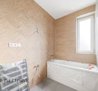 Na predaj zrekonštr. 3-izb. byt s balkónom, Dun.Streda - Kúpeľňa s vaňou a stenou v drevenom dekore v 3-izbovom byte.
