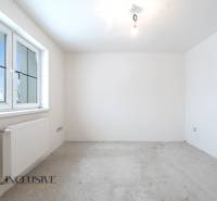 Na predaj poschodový 6-izbový rodinný dom, Horné Mýto - Prázdna izba v rodinnom dome s betónovou podlahou a veľkým oknom.