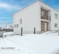 Na predaj poschodový 6-izbový rodinný dom, Horné Mýto - Rodinný dom v Hornom Mýte pokrytý snehom s tehlovým vstupom a balkónom.