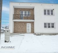 Na predaj poschodový 6-izbový rodinný dom, Horné Mýto - Rodinný dom v Hornom Mýte so snehovou pokrývkou a tehlovými detailmi na fasáde.