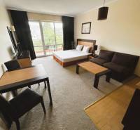 Štúdio DIT Majestic Beach Resort v 1. línií pri mori Bulharsko  - 1-izbový byt so svetlou obývačkou, tmavým nábytkom a podlahou s dreveným dekorom.