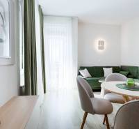 Na predaj 3 izbový byt s terasou, Trenčín, ul. Saratovská - Obývacia izba s podlahou s dreveným dekorom, zelenou sedačkou a jedálenským stolom v 3-izbovom byte.