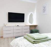 Na predaj 3 izbový byt s terasou, Trenčín, ul. Saratovská - Spálňa s televízorom, zrkadlom a komodou v 3-izbovom byte, podlaha s dreveným dekorom.