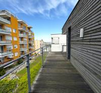 Na predaj veľký 2-izbový byt s terasou a wellness - Koliba - Balkón s drevenou podlahou a výhľadom na bytové domy na ulici Tupého v Bratislave.