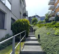 Na predaj veľký 2-izbový byt s terasou a wellness - Koliba - Schody vedú popri moderných budovách a zeleni na ulici Tupého v Bratislave.
