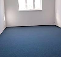 Prenájom klimatizovaná kancelária: 25 m2 a 42 m2 - Trnava Chovateľská - Kancelárie s modrým kobercom a oknom, umiestnené na Chovateľskej ulici v Trnave.