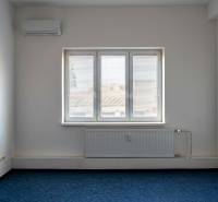 Prenájom klimatizovaná kancelária: 25 m2 a 42 m2 - Trnava Chovateľská - Izba s klimatizáciou a oknom v Kanceláriách, modrý koberec, biele steny.