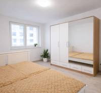 NOVOSTAVBA (2019) + PARKOVANIE | 2-izbový byt 69 m² – Bratislava - Interiér spálne v 2-izbovom byte s bielou skriňou a podlahou s dreveným dekorom.