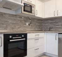 NOVOSTAVBA (2019) + PARKOVANIE | 2-izbový byt 69 m² – Bratislava - Kuchyňa v 2-izbovom byte s bielymi skrinkami a vstavanými spotrebičmi.