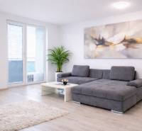 NOVOSTAVBA (2019) + PARKOVANIE | 2-izbový byt 69 m² – Bratislava - Obývačka v 2-izbovom byte ponúka pohodlnú sedačku a podlahu s dreveným dekorom.