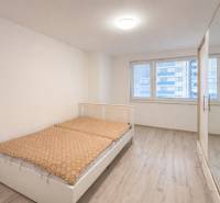 NOVOSTAVBA (2019) + PARKOVANIE | 2-izbový byt 69 m² – Bratislava - Spálňa s posteľou a šatníkovou skriňou, podlaha s dreveným dekorom v 2-izbovom byte.