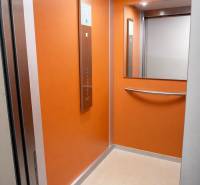 NOVOSTAVBA (2019) + PARKOVANIE | 2-izbový byt 69 m² – Bratislava - Interiér oranžového výťahu so zrkadlom a ovládacím panelom.