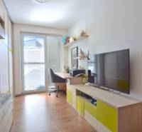 UHLISKÁ, 3-i byt, 80 m2 – zariadená novostavba s parkovaním v cene - Izba s podlahou s dreveným dekorom, pracovným stolom a televízorom v 3-izbovom byte.