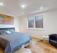 4-IZBOVÁ NOVOSTAVBA Horné Štitáre - Spálňa s pohodlným kreslom, taburetkou, veľkou posteľou a podlahou s dreveným dekorom.