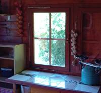 TURANY- krásna chata na pozemku 700m2 - Interiér drevenej chatky so starožitnou váhou, kuchynským kútikom a výhľadom na zeleň.