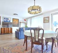 PRI VINOHRADOCH, 3-i byt s veľkými loggiami, 113 m2, RAČANY BIANCO - Obývacia izba s jedálenským stolom, pohovkou a podlahou s dreveným dekorom v 3-izbovom byte.