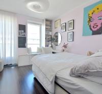 PRI VINOHRADOCH, 3-i byt s veľkými loggiami, 113 m2, RAČANY BIANCO - Spálňa v 3-izbovom byte s podlahou s dreveným dekorom a umeleckými obrazmi na stene.