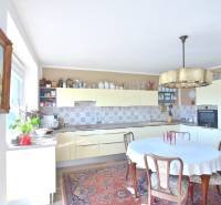 PRI VINOHRADOCH, 3-i byt s veľkými loggiami, 113 m2, RAČANY BIANCO - Kuchyňa v 3-izbovom byte s dreveným nábytkom, kvetinami a vzorovaným kobercom.