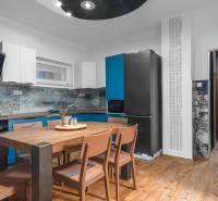 I Predaj štýlového tehlového domu v Rajke pri Bratislave - Kuchyňa v rodinnom dome s dreveným stolom a podlahou s dreveným dekorom.