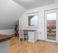 I Predaj štýlového tehlového domu v Rajke pri Bratislave - Interiér rodinného domu s podlahou s dreveným dekorom, písací stôl a stolička.