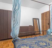 I Predaj štýlového tehlového domu v Rajke pri Bratislave - Spálňa v rodinnom dome s podlahou s dreveným dekorom, vzorované závesy a zrkadlo.