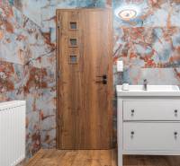 I Predaj štýlového tehlového domu v Rajke pri Bratislave - Kúpeľňa v rodinnom dome s farebnými stenami, drevenými dverami a umývadlom.
