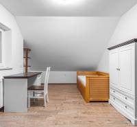 I Predaj štýlového tehlového domu v Rajke pri Bratislave - Izba v rodinnom dome s dreveným nábytkom a podlahou s dreveným dekorom.