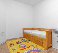 I Predaj štýlového tehlového domu v Rajke pri Bratislave - Jednolôžková posteľ s úložným priestorom, koberec so vzorom, podlaha s dreveným dekorom.