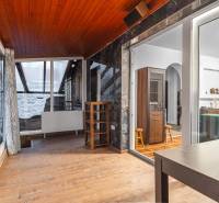 I Predaj štýlového tehlového domu v Rajke pri Bratislave - Interiér rodinného domu s podlahou s dreveným dekorom, presklená stena, závesy, stoličky.