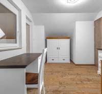 I Predaj štýlového tehlového domu v Rajke pri Bratislave - Izba v rodinnom dome s podlahou s dreveným dekorom, stolom a bielym nábytkom.