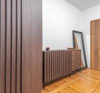 I Predaj štýlového tehlového domu v Rajke pri Bratislave - Interiér rodinného domu s komodou, zrkadlom a podlahou s dreveným dekorom.