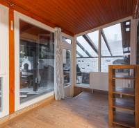 I Predaj štýlového tehlového domu v Rajke pri Bratislave - Interiér rodinného domu s presklenou stenou, závesmi a podlahou s dreveným dekorom.