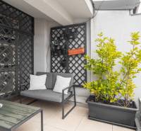 I Exkluzívny penthouse s terasou v absolútnom centre mesta - Balkón v 2-izbovom byte s pohovkou, rastlinami a dekoratívnou mrežovou stenou.