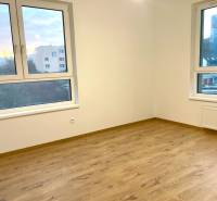 I Predaj 3i bytu v novostavbe v Rači - Prázdna miestnosť s podlahou s dreveným dekorom a veľkými oknami v 3-izbovom byte.