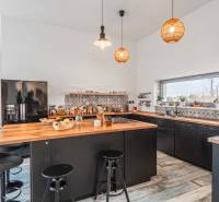 I PREDAJ moderná vila s bazénom a veľkým pozemkom - Kuchyňa v rodinnom dome s čiernym nábytkom, dreveným dekorom a veľkým oknom.