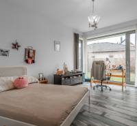 I PREDAJ moderná vila s bazénom a veľkým pozemkom - Spálňa vo Vile s posteľou, stolom, stoličkou a podlahou s dreveným dekorom.