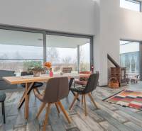 I PREDAJ moderná vila s bazénom a veľkým pozemkom - Interiér Vily s podlahou s dreveným dekorom, jedálenským stolom a veľkými oknami.