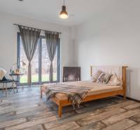 I PREDAJ moderná vila s bazénom a veľkým pozemkom - Spálňa vo vile s posteľou, písacím stolom, závesmi a podlahou s dreveným dekorom.